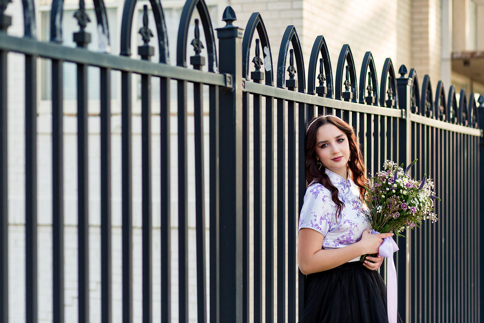 Isabella leans against a wrought-iron fence.