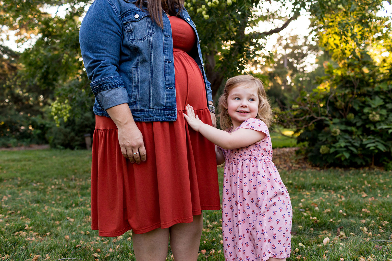 Ellie reaches out to her mama's belly, offering her baby sister a friendly hello.