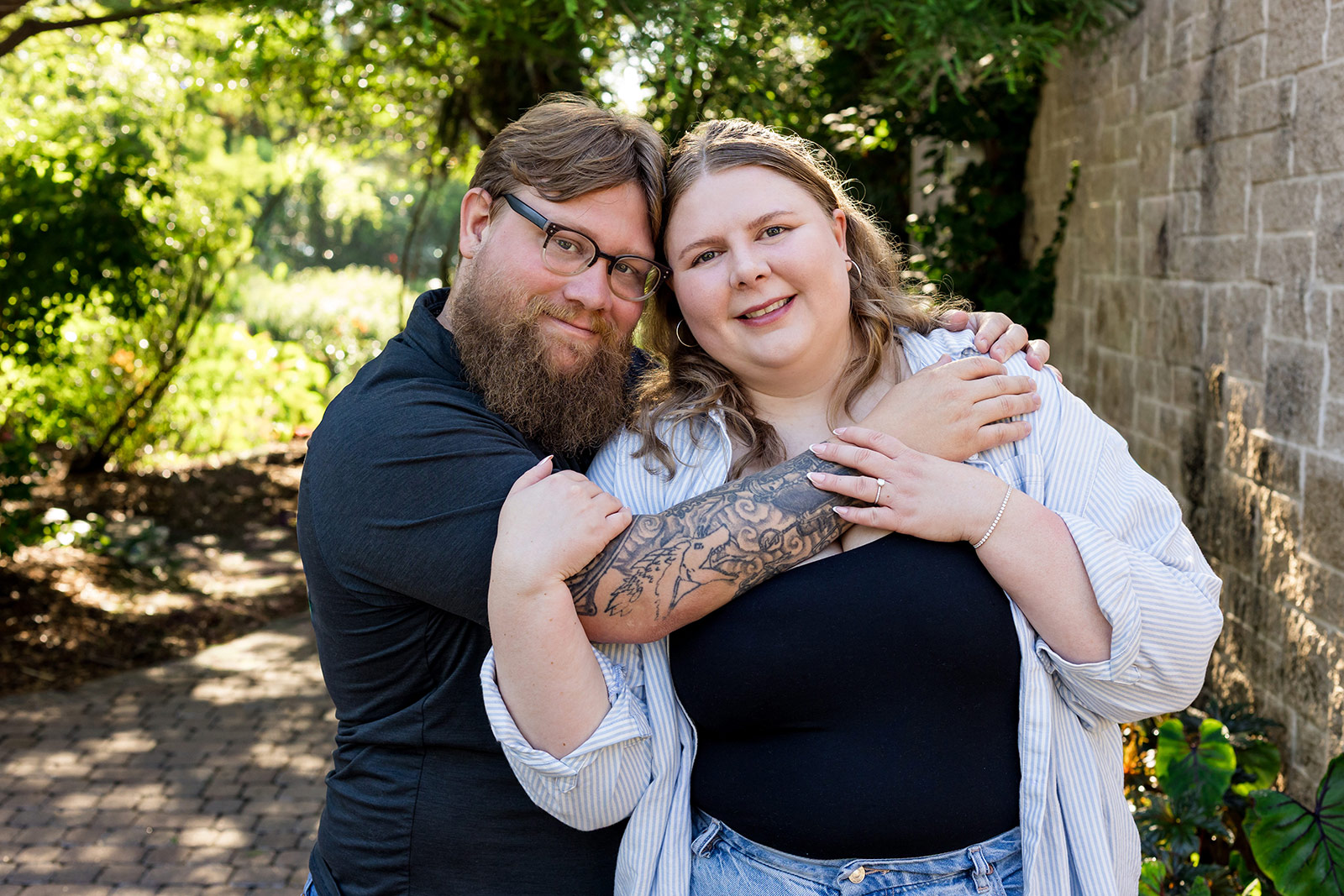 Parents embracing and smiling at the camera during a natural couples portrait at Sunken Gardens in Lincoln, Nebraska.